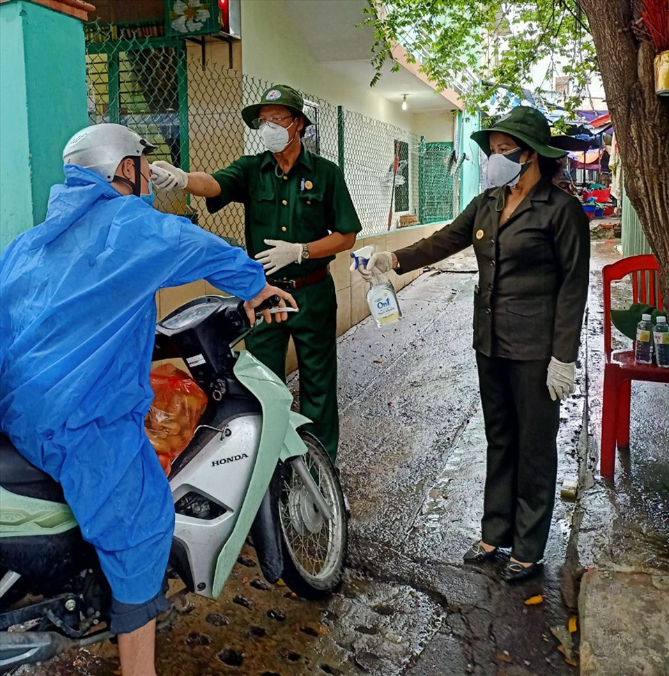 Cựu chiến binh phường Chính Gián (quận Thanh Khê) đo thân nhiệt và hỗ trợ nước rửa tay sát khuẩn cho người dân. Ảnh: Lê Văn Thơm