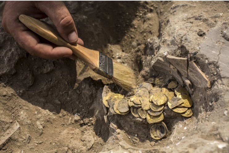Nhà khảo cổ học người Israel, Shahar Krispin, dọn dẹp những đồng tiền vàng được phát hiện tại một địa điểm khảo cổ ở miền trung Israel. Ảnh: AP.