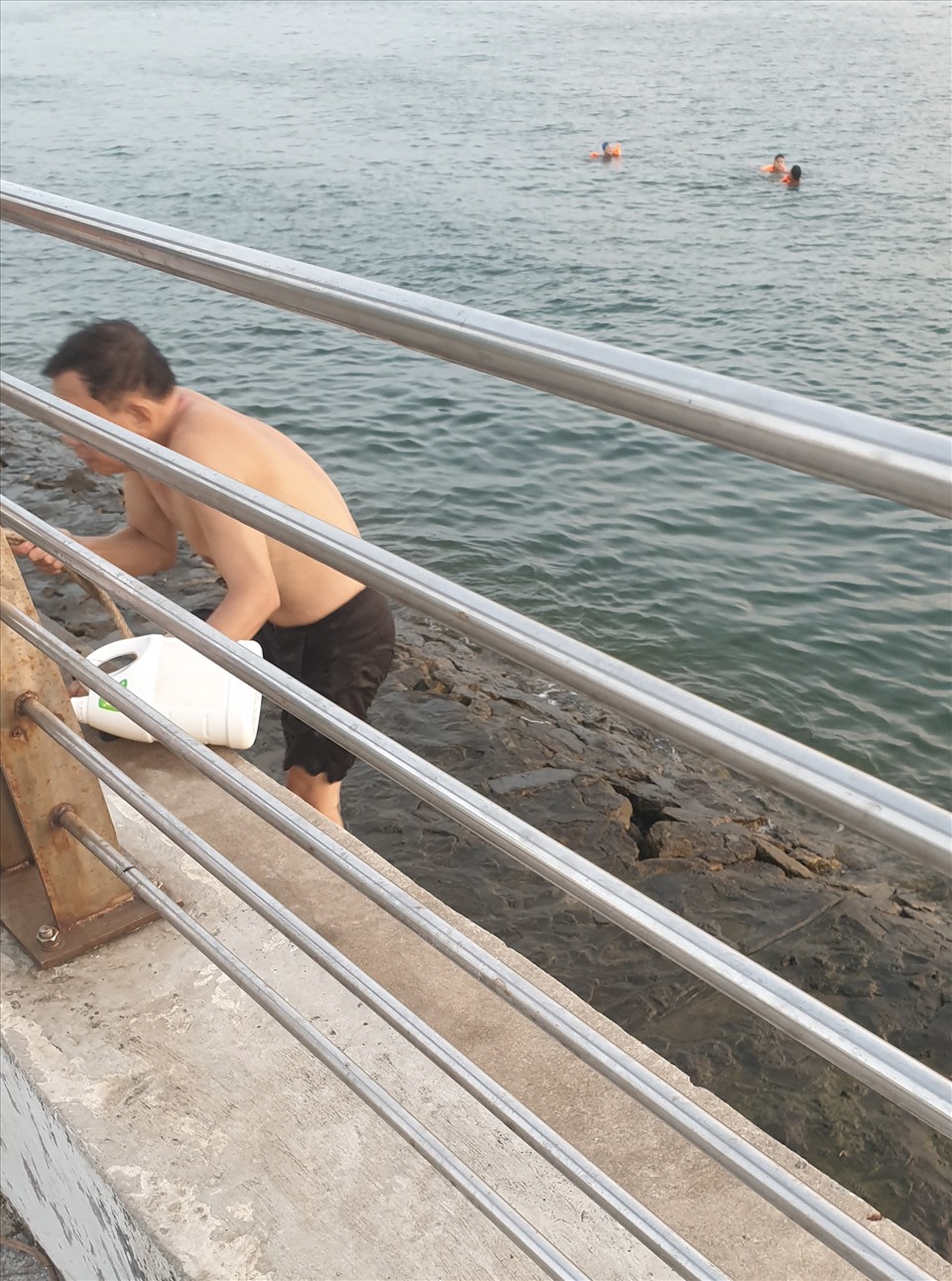 Một người dân đu dây, leo thang lên bờ sau khi tắm. Ảnh: Nguyễn Hùng