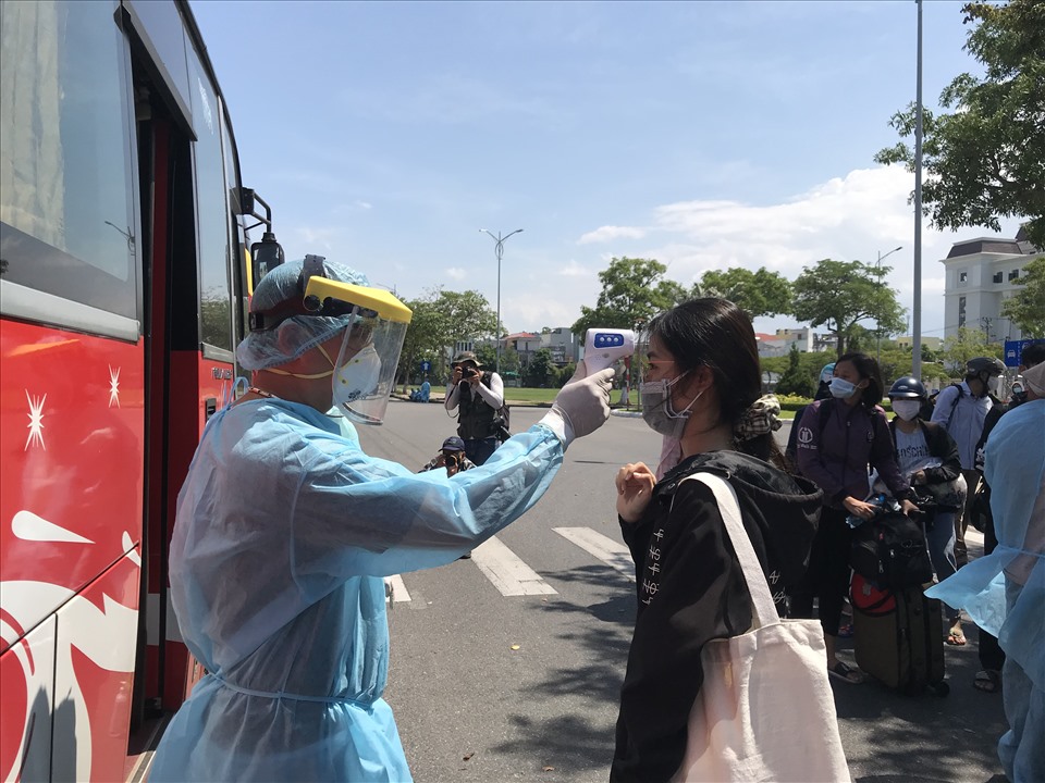 Lực lượng chức năng đo thân nhiệt cho người dân trước khi lên xe từ Đà Nẵng trở về Đắk Nông. Ảnh: Mai Hương