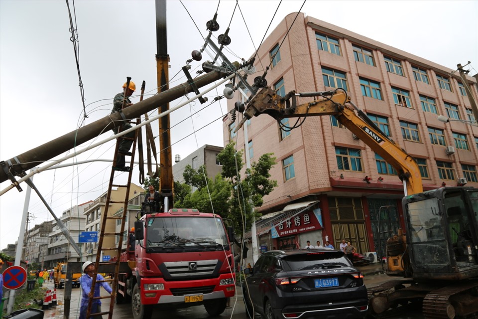Thợ điện sửa chữa một cột dây điện bị sập ở tỉnh Chiết Giang vào ngày 4.8. Ảnh: China Daily