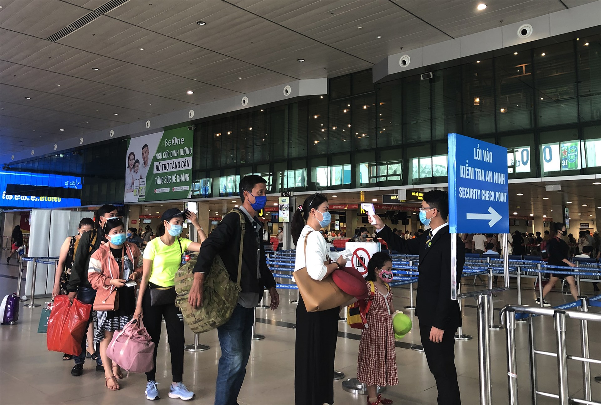 Hành khách đeo khẩu trang, đo thân nhiệt trước khi qua cửa an ninh tại sân bay Tân Sơn Nhất. Ảnh: T.T