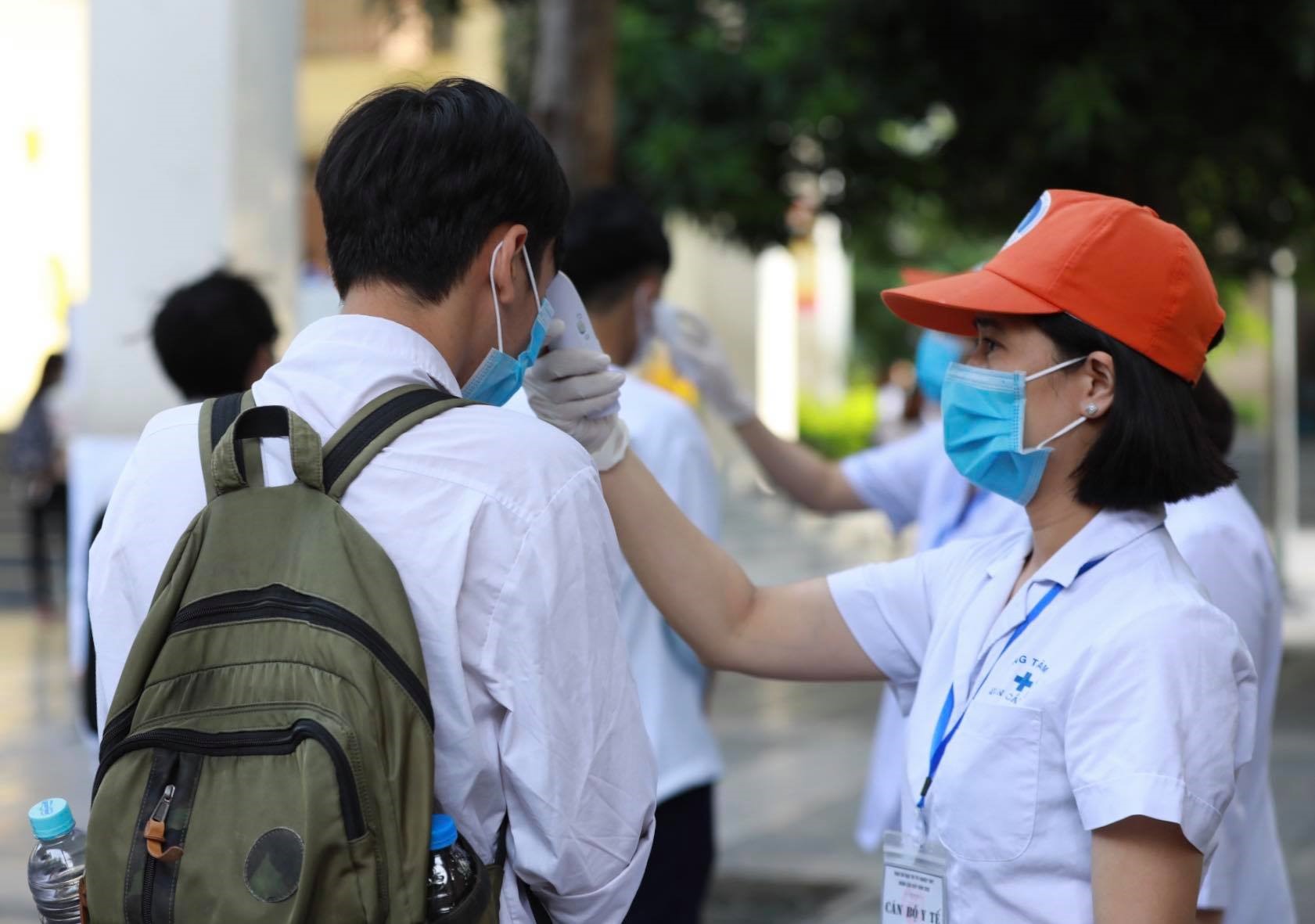 Thí sinh xếp hàng đo thân nhiệt trước khi vào phòng thi tại điểm Trường THCS Nghĩa Tân (Hà Nội). Ghi nhận của Hải Nguyễn sáng 10.8.