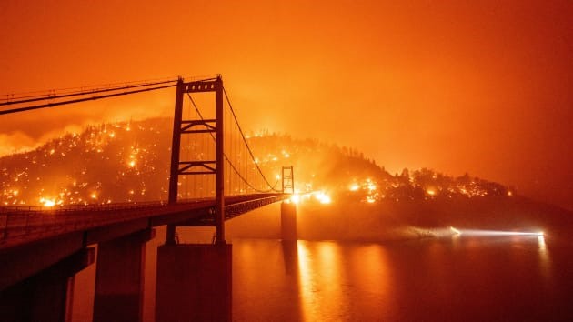 Một chiếc thuyền chạy ngang qua cầu Bidwell Bar đang bị bao vây từ đám cháy Bear ở hồ Oroville, California hôm 9.9. Ảnh: AFP.
