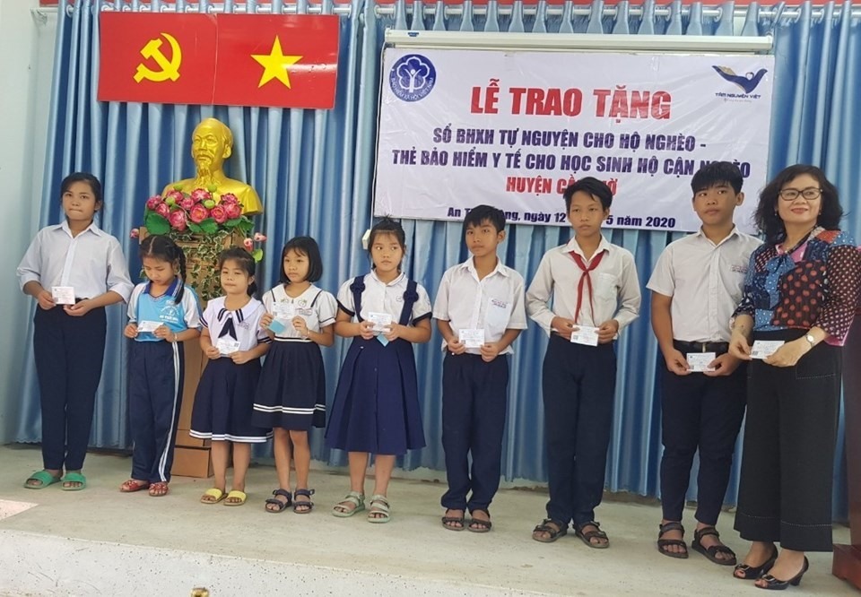 Đại diện Quỹ Tâm nguyện Việt trao thẻ BHYT cho học sinh có hoàn cảnh khó khăn trên địa bàn huyện Cần Giờ. Ảnh BHXH TPHCM cung cấp