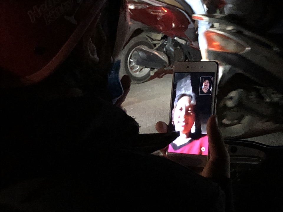Một nữ công nhân tranh thủ gọi điện video cho người thân trong lúc tắc đường. Ảnh: Bảo Hân.