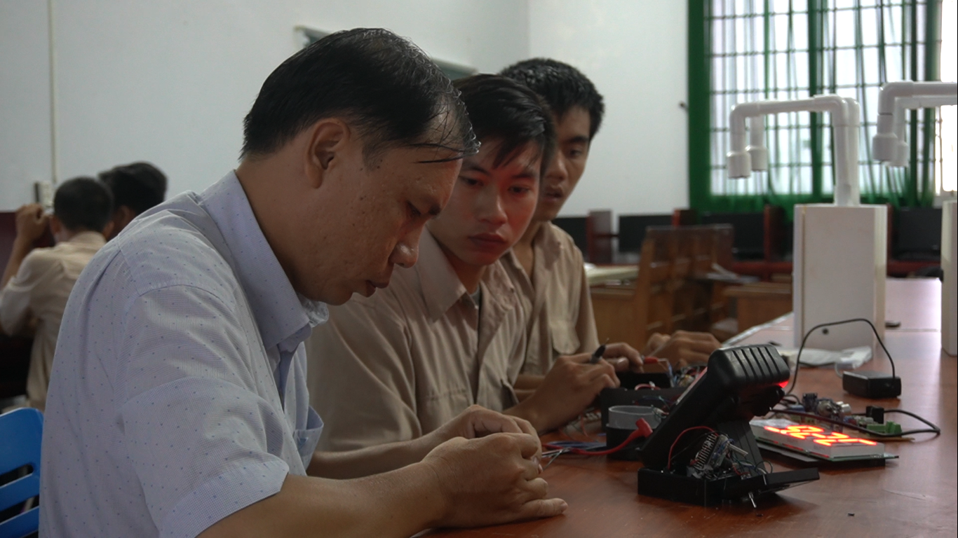Thầy Lê Trung Kiên, Giảng viên Khoa Điện - Điện tử máy tính trường Cao đẳng Nghề Kiên Giang cùng các sinh viên kiểm tra lại hoạt động của máy đo thân nhiệt và sát khuẩn tay tự động. Ảnh: PV