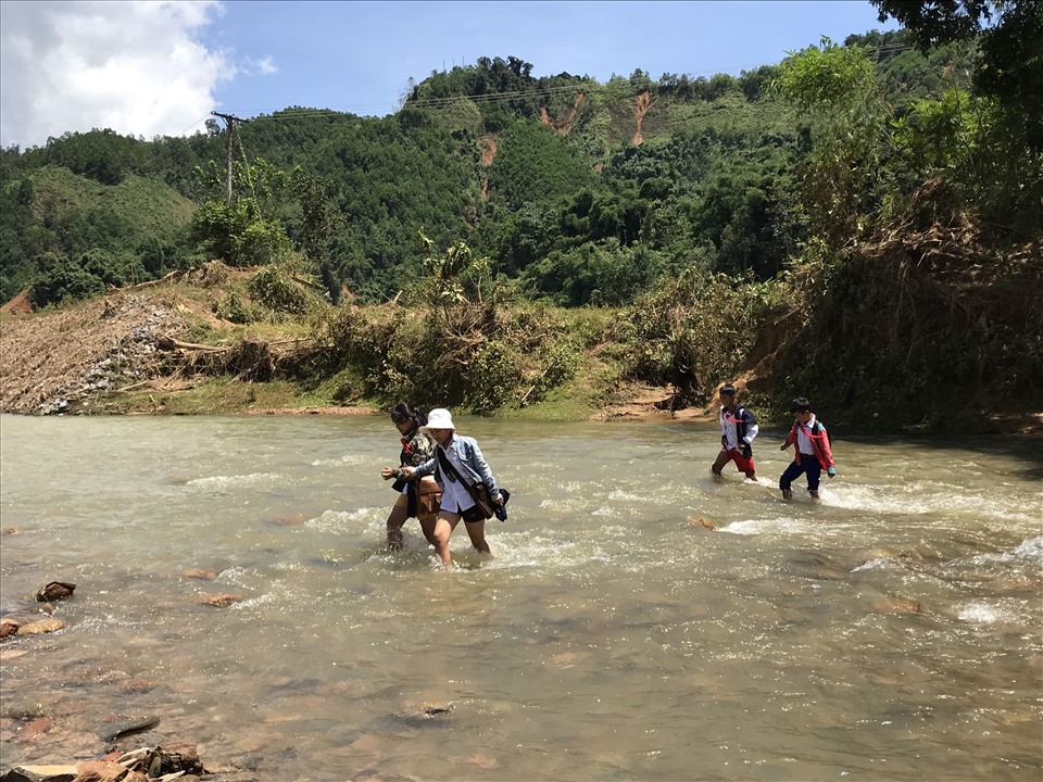 Một số học sinh tại thôn Tà Làng băng qua dòng nước chảy xiết đến trường trong ngày học đầu tiên sau trận lũ lịch sử “càng quét“.