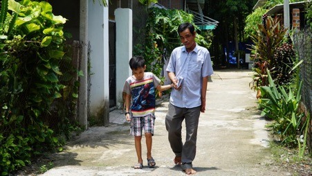Hai cha con bé Bình Minh dắt tay nhau đến trường.