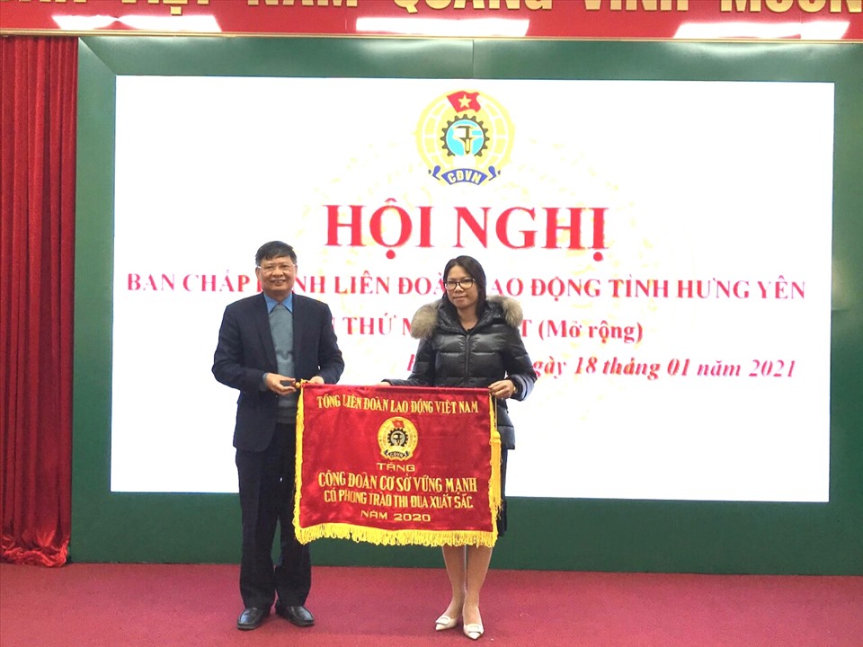 Phó Chủ tịch Tổng LĐLĐVN Phan Văn Anh (bên trái) trao tặng Cờ thi đua của Tổng LĐLĐVN cho CĐCS Công ty may Hưng Long 2. Ảnh: Thu Nguyệt