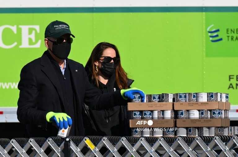 Tổng thống đắc cử Mỹ Joe Biden (L), đứng cùng con gái Ashley, dọc theo băng chuyền được thiết lập ở bãi đậu xe bên ngoài, đóng gói thực phẩm quyên góp tại Philabundance, tổ chức cứu trợ nạn đói lớn nhất của Philadelphia ở Philadelphia, Pennsylvania vào ngày 18 tháng 1 năm 2021.