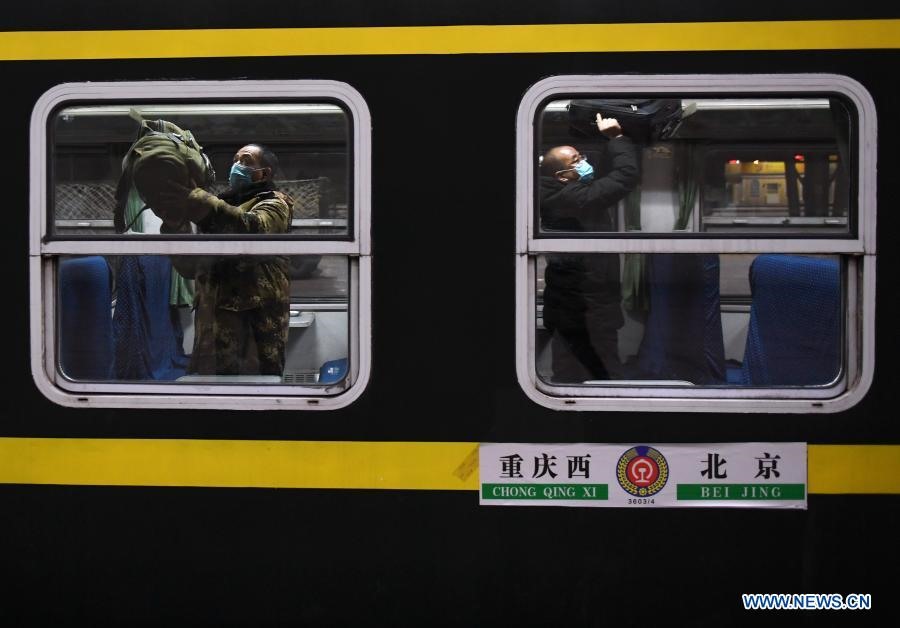 Hành khách đặt hành lý lên kệ trên chuyến tàu 3603 từ Bắc Kinh đến Trùng Khánh hôm 28.1.2021. Ảnh: Tân Hoa Xã.