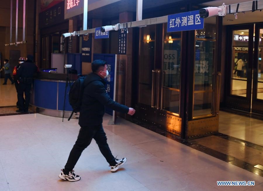 Hành khách đi qua khu vực đo nhiệt độ bằng tia hồng ngoại khi bước vào ga tàu Bắc Kinh hôm 27.1. Ảnh: Tân Hoa Xã.