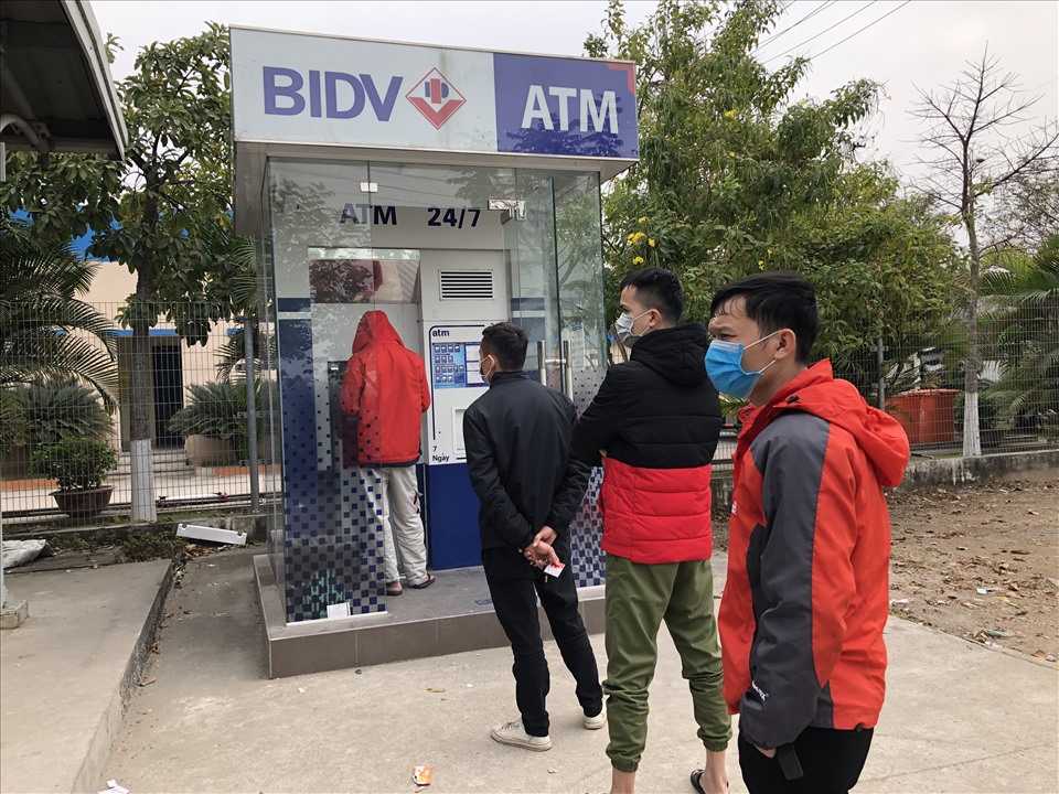 Công nhân đeo khẩu trang, xếp hàng trong lúc chờ rút tiền từ cây ATM. Ảnh: Bảo Hân
