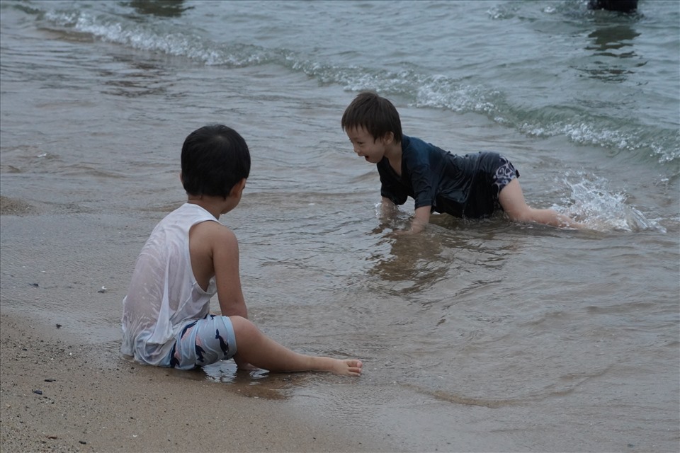 Nhiều em bé được phụ huynh đưa ra biển từ sáng sớm. Các em hào hứng chơi đùa trong làn nước mát, hoặc nghịch cát trên bờ. Ảnh: T.A