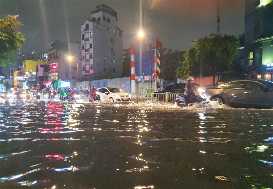 Người dân chạy xe máy sát dải phân cách tránh khu vực ngập sâu.  Ảnh: Chân Phúc