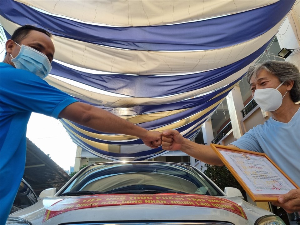Ông Võ Khắc Bình tặng Giấy khen của LĐLĐ Quận 7 cho anh Nguyễn Trung Tính, một tình nguyện viên của Đội vận chuyển thuốc điều trị cho F0. Ảnh: Nam Dương