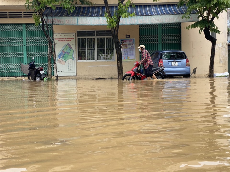 Người dân cố gắng dắt xe qua đoạn ngập lụt. Ảnh: D.P