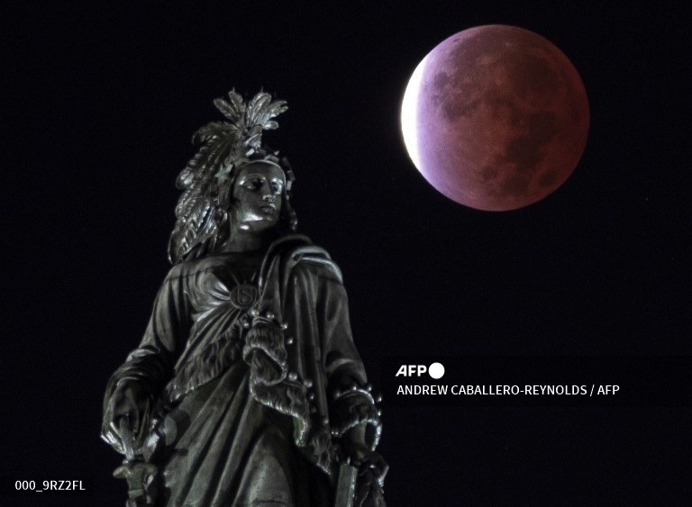 Mặt trăng được nhìn thấy phía sau Tượng Tự do, trên đồi Capitol ở Washington, DC (Mỹ). Ảnh: AFP