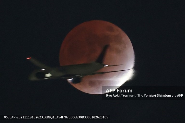 Cảnh tượng một chiếc máy bay đang bay phía trước Mặt trăng ở Koto Ward, Tokyo, Nhật Bản. Ảnh: AFP