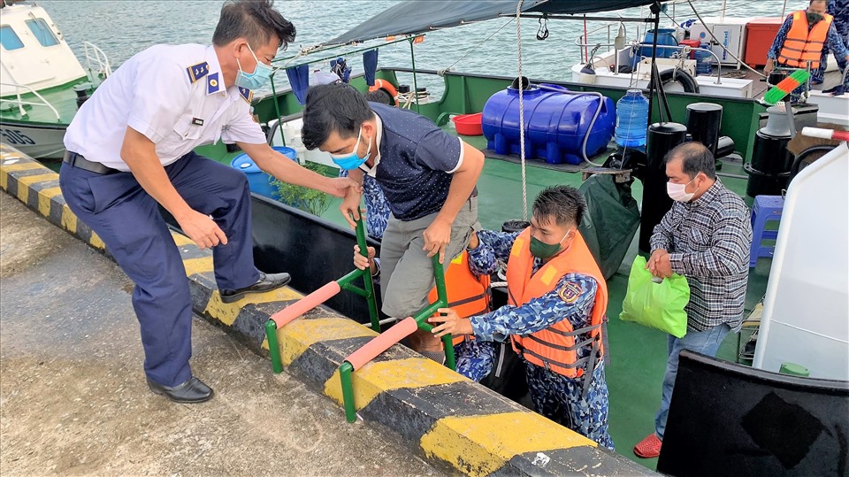 Cảnh sát biển giúp ngư dân bị bệnh lên bờ để đưa đến bệnh viện cấp cứu. Ảnh: Hoàng Dung