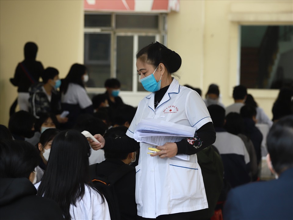 Nhân viên y tế kiểm tra thân nhiệt cho học sinh.