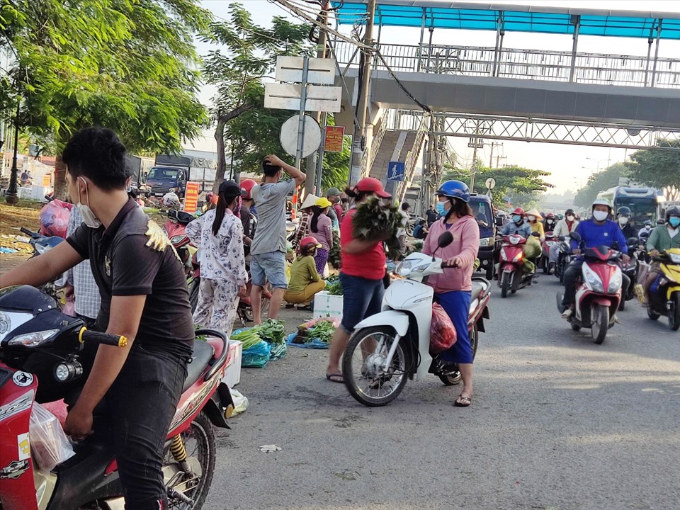 Nhiều người bày bán rau củ trên Quốc lộ 1A trước chợ đầu mối nông sản Thủ Đức.  Ảnh: Minh Quân