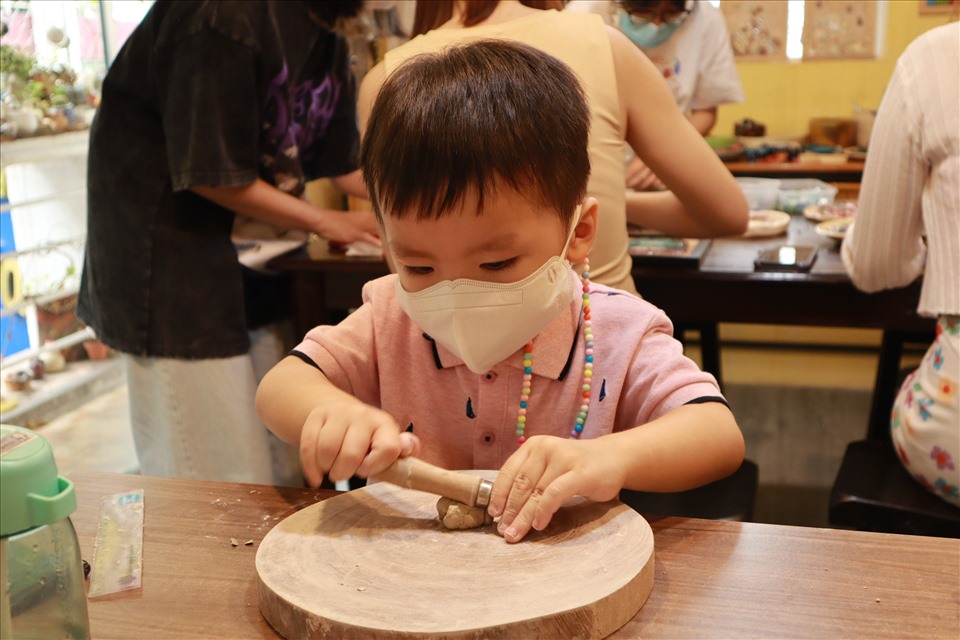 Ở một góc khác của xưởng, đối với những em bé đến xưởng làm gốm như ở một thiên đường sáng tạo đầy thích thú. Cầm nắm đất màu xám trên tay, bé Nguyễn Minh Thiên miệt mài nhào nặn những gì mình thích.
