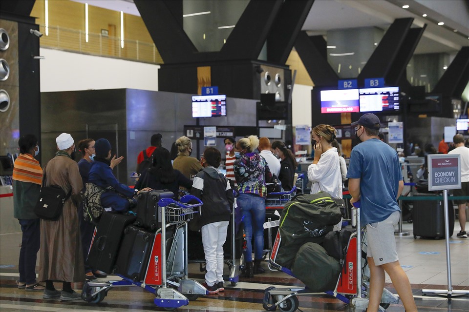 Du khách xếp hàng tại quầy làm thủ tục ở sân bay quốc tế OR Tambo, Johannesburg, Nam Phi, ngày 27.11.2021, sau khi một số quốc gia áp dụng các hạn chế đi lại mới do biến thể Omicron. Ảnh: AFP