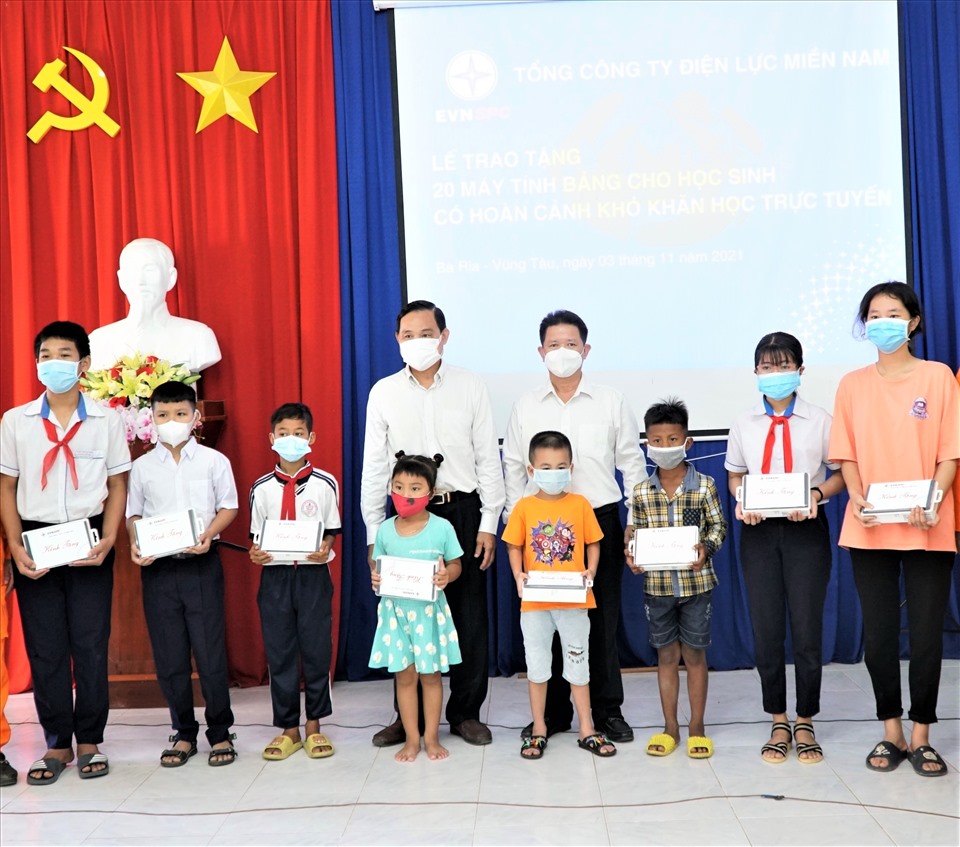 Ông Nguyễn Văn Hợp - Chủ tịch HĐTV EVNSPC (bìa trái hàng phía sau) trao máy tính bảng cho các em học sinh. Ảnh EVNSPC cung cấp