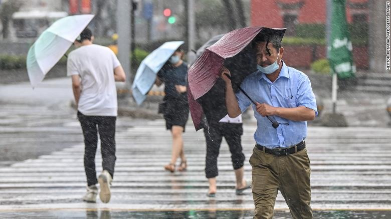 Người dân băng qua đường trong mưa gió ở Ninh Ba ngày 25.7.2021 khi cơn bão In-fa tấn công bờ biển phía đông Trung Quốc. Ảnh: AFP