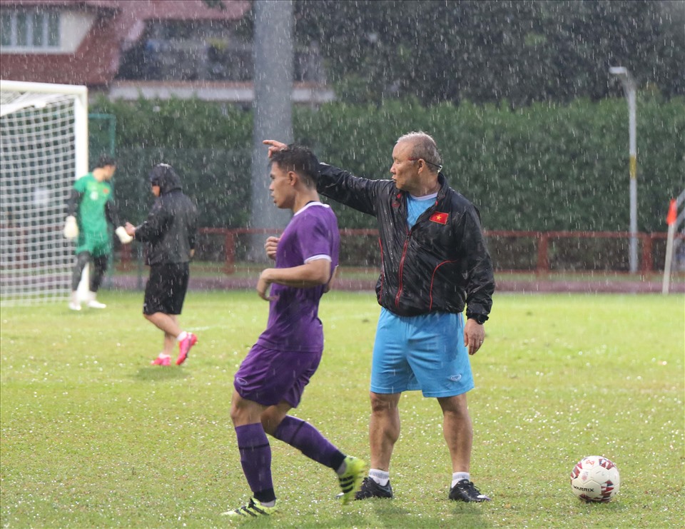 Thầy Park dầm mưa cùng các học trò. Ông tập trung quan sát, chỉnh sửa động tác cho từng cầu thủ. ẢNh: VFF