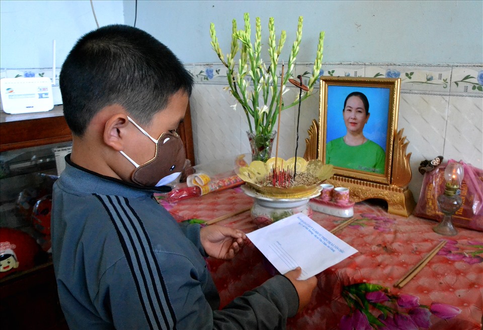 Cháu Lê Nguyễn Công Danh (8 tuổi) mang số tiền hõ trợ trình lên bàn thờ mẹ. Ảnh: LT