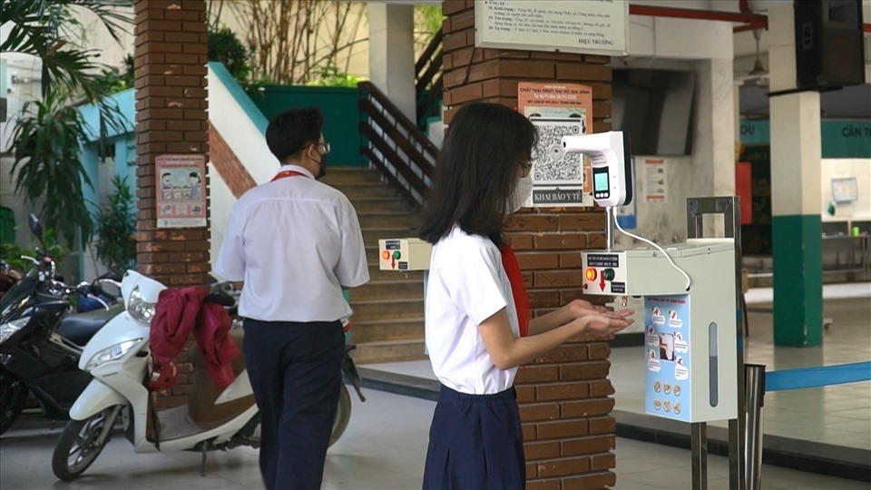 Học sinh đo nhiệt độ trước khi vào trường học. Ảnh: Anh Tú.
