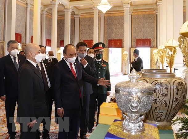 Chủ tịch nước Nguyễn Xuân Phúc và Quốc vương Campuchia Norodom Sihamoni giới thiệu về của quà tặng của 2 nước tại Cung điện Hoàng gia. Ảnh: TTXVN