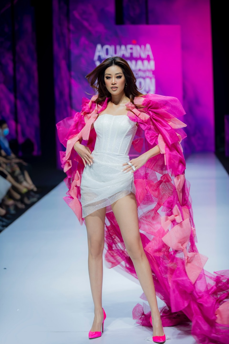 Hoa hậu Hoàn vũ 2019 - Khánh Vân diện thiết kế ấn tượng với đầm body màu trắng kết hợp cùng áo choàng màu hồng được đính kết các chi tiết nơ tinh tế.