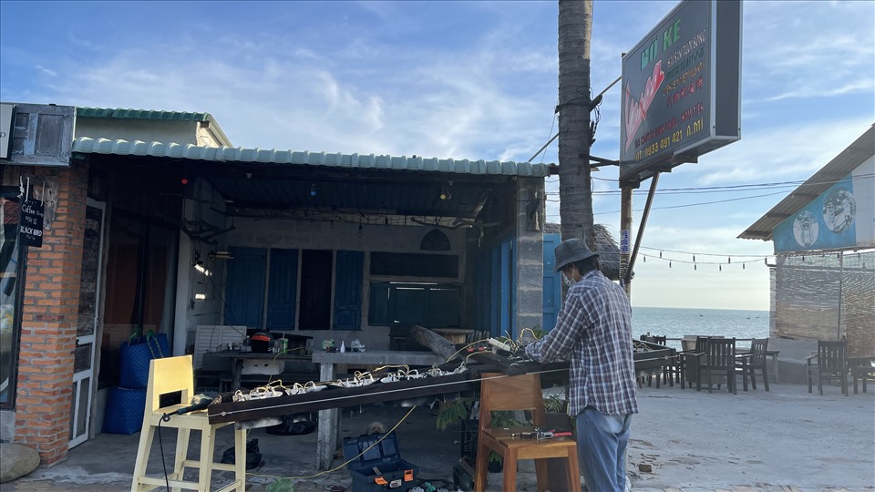 Một quán cà phê “view biển” thu hút giới trẻ check-in đang sửa lại phần đèn trang trí. Ảnh: DT