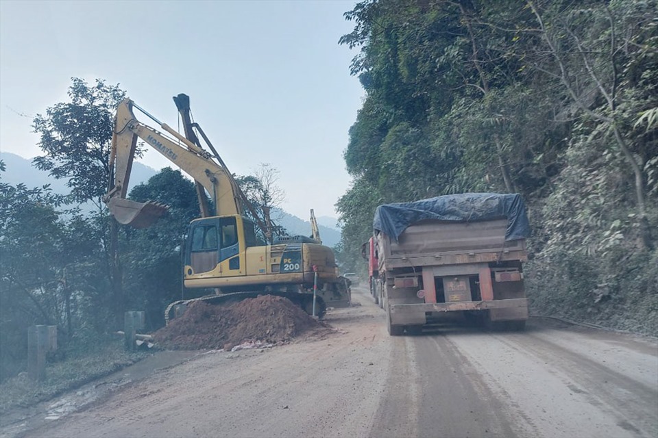 Máy đào thi công đường phải tạm né ra để xe qua lại. Ảnh: TT.