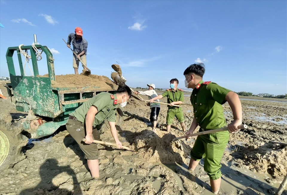 Lực lượng công an huyện Tuy Phước giúp người dân dọn dẹp ruộng bị đất bồi lấp.