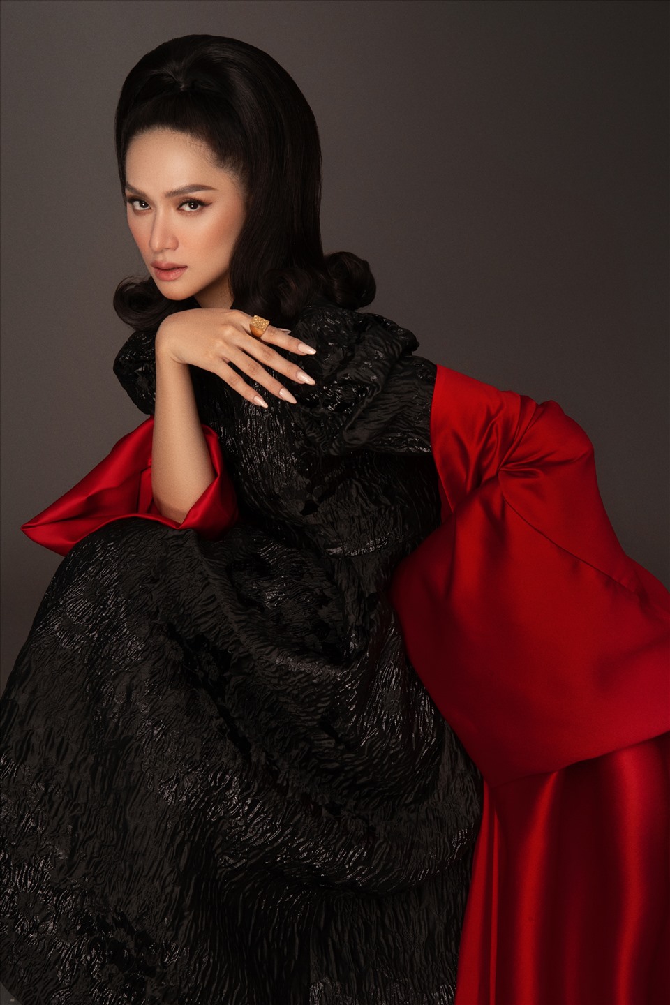 Trong bộ sưu tập mới của SIXDO, Hoa hậu Hương Giang điệu đà, nữ tính với chiếc đầm đen kín đáo. Điểm nhấn là phần tay bồng mang phong cách cổ điển kết hợp áo choàng màu đỏ tạo nên một vẻ đẹp đầy bí hiểm. Ảnh: Milor Trần