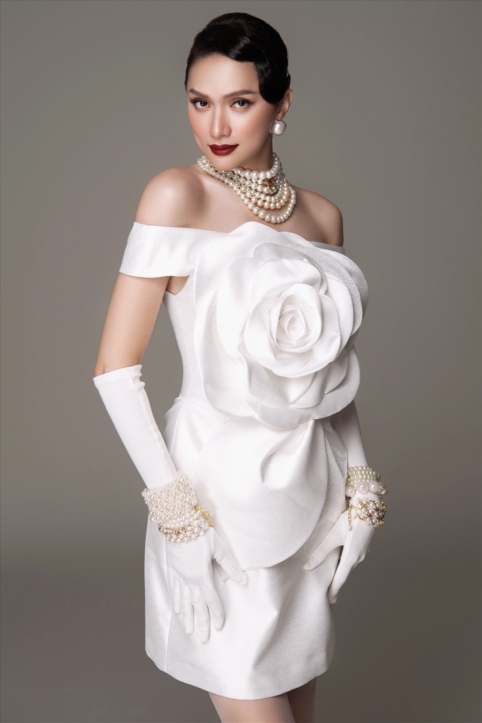 Người đẹp nổi bật khi diện váy màu trắng có chi tiết hoa trà 3D to bản. Hương Giang mang nhiều phụ kiện ngọc trai cầu kỳ, tô son đỏ đậm thêm phần ấn tượng. Trang phục hoa trà cũng là điểm đặc trưng trong BST mới của Đỗ Mạnh Cường,
