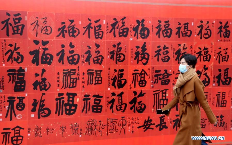 Một người phụ nữ đi bộ qua một tấm áp phích có chữ “phúc” chuẩn bị cho Tết Nguyên đán ở thành phố Thường Châu, tỉnh Giang Tô, phía đông Trung Quốc. Ảnh: Tân Hoa Xã
