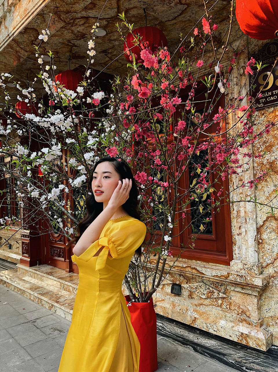 Cũng là áo dài trơn đơn giản nhưng Hoa hậu Lương Thuỳ Linh lựa chọn áo dài vàng nổi bật.