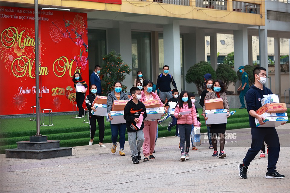 Học sinh và phụ huynh trường Tiểu học Xuân Phương mang đồ rời khu cách ly vào sáng mùng 3 Tết.