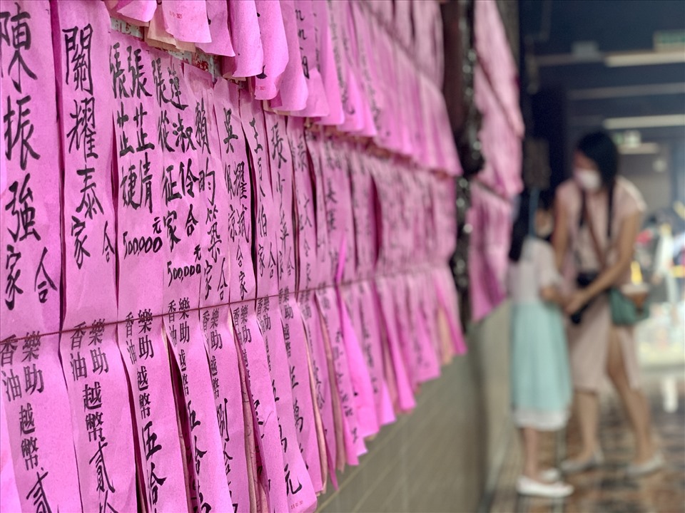 Hai bên lối đi của ngôi chùa là những tời giấy màu hồng dán thẳng hàng, trên đó ghi tên những nhà hảo tâm đóng góp cho nhà chùa.