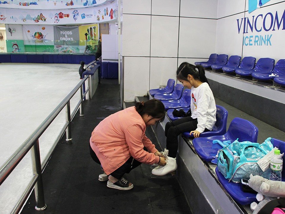 Buộc dây giày trượt băng cho Tâm Nhi là việc làm thường xuyên của dì Tâm Nhi mỗi khi ra sân tập. Ảnh: Linh Nguyên