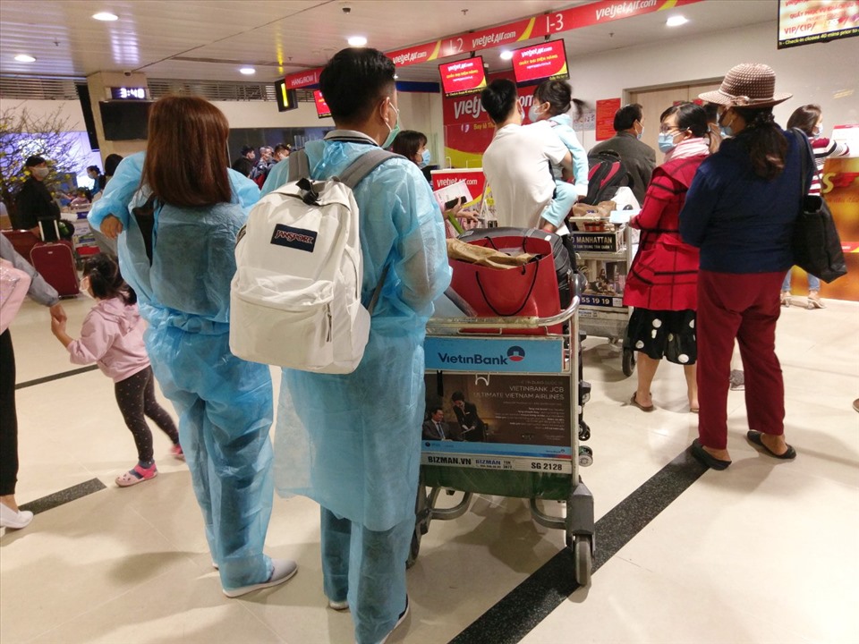 Một gia đình mặc đồ bảo vệ chờ làm thủ tục lên máy bay ở sân bay Tân Sơn Nhất.