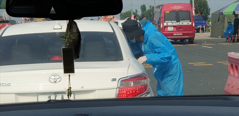 Đo thân nhiệt và kiểm tra giấy tờ tùy thân của lái xe và hành khách trước khi vào Quảng Ninh tại Trạm thu phí cầu Bạch Đằng chiều 11.3. Ảnh: Nguyễn Hùng