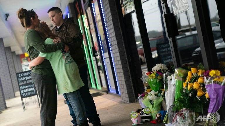 Mọi người ôm nhau bên ngoài cửa tiệm Youngs Asian Massage tại Mỹ, nơi có 4 người thiệt mạng trong vụ xả súng. Ảnh: AFP