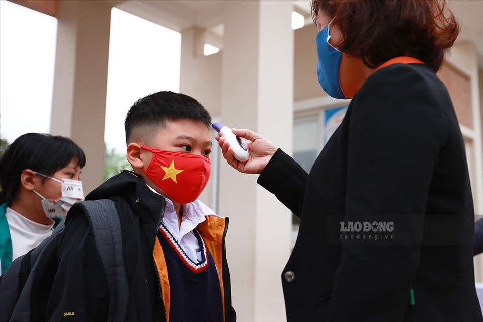 Cô giáo đo thân nhiệt cho học sinh trước khi vào lớp. Ảnh Hải Nguyễn